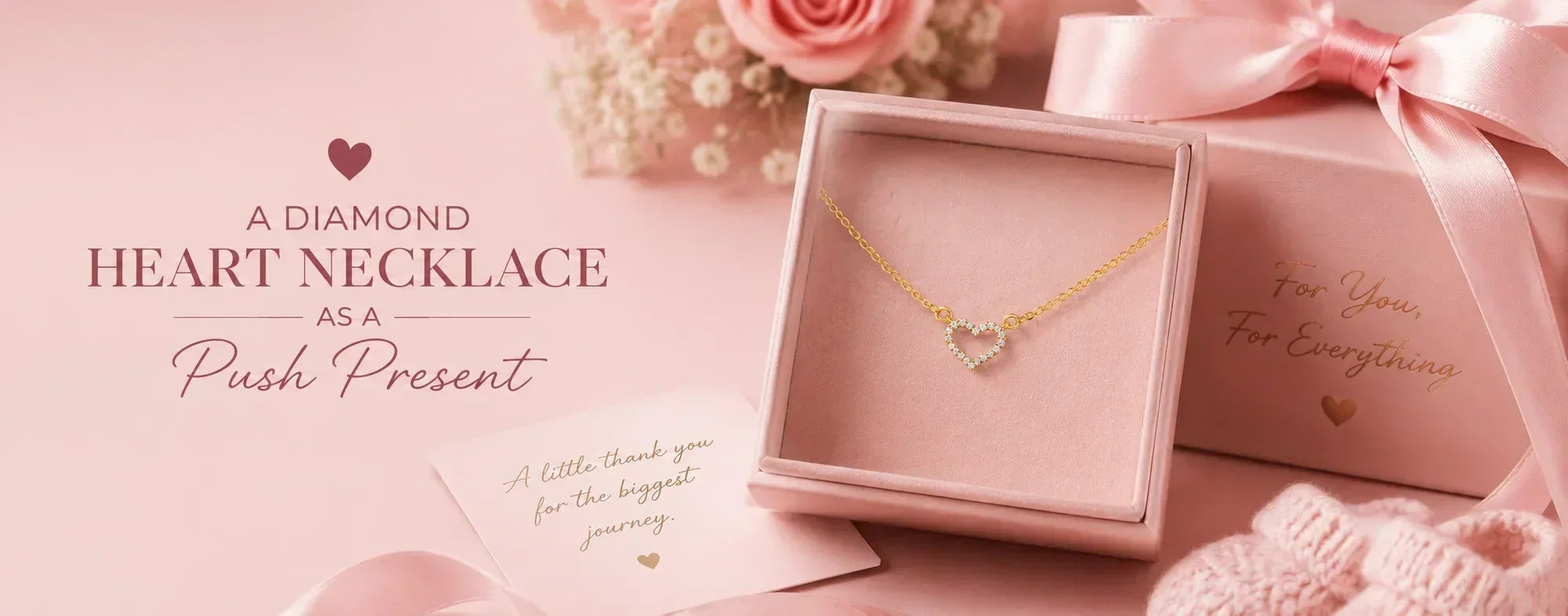 A pink-themed hero image featuring a diamond heart necklace in a jewelry box, surrounded by soft pink gifts, flowers, and a ribbon, with text reading “A Diamond Heart Necklace as a Push Present.”