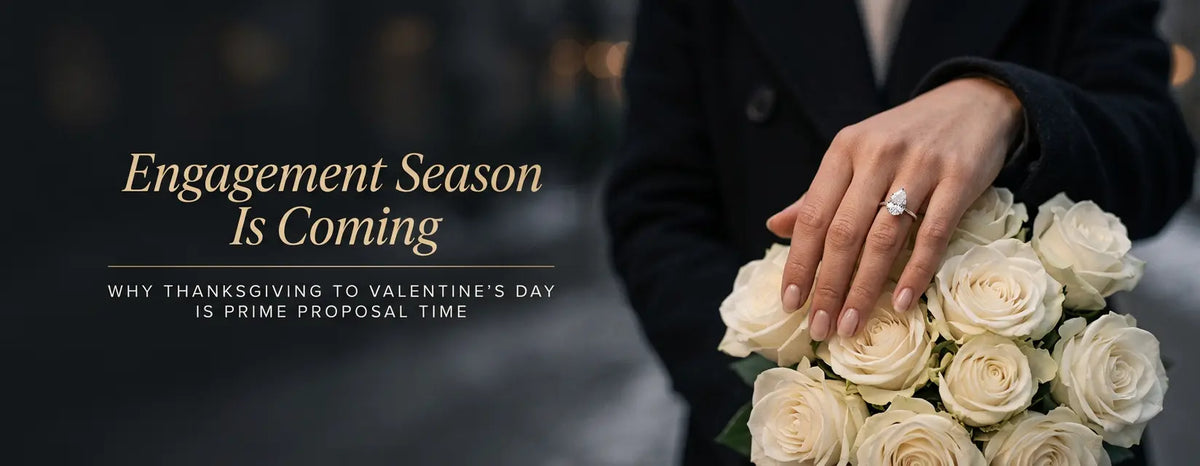 Pear-shaped diamond engagement ring on a hand holding white roses at the start of engagement season