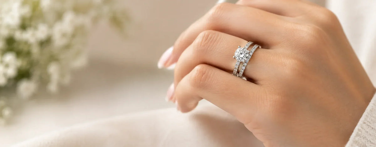 Engagement ring and wedding band worn together in a traditional stack, with the wedding band closest to the hand
