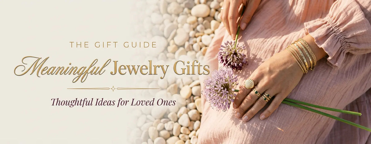 Woman's hand with stacked gold bracelets and rings holding a lavender allium flower, a meaningful jewelry gift idea