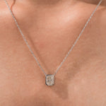 Model wearing a classic 18K yellow gold radiant Diamond necklace featuring an elongated bezel-set solitaire pendant.