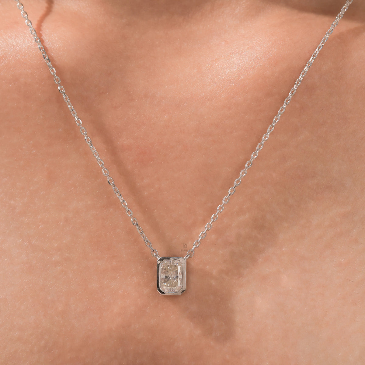 Model wearing a classic 18K yellow gold radiant Diamond necklace featuring an elongated bezel-set solitaire pendant.
