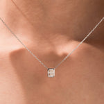 Model wearing a classic yellow gold radiant Diamond necklace featuring an elongated bezel-set solitaire pendant.