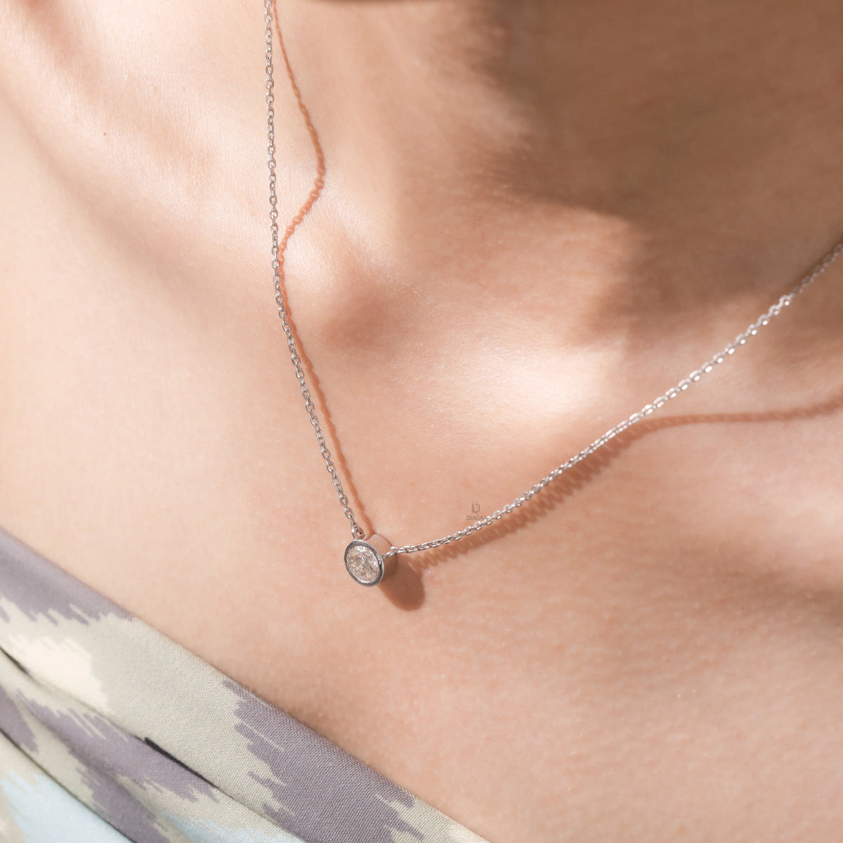 Model wearing an elegant Round Diamond necklace with a bezel-set solitaire diamond on a fine white gold chain.