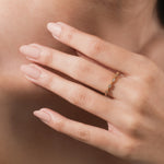 A delicate yellow gold eternity ring featuring an alternating pattern of baguette diamonds worn on a woman's finger.