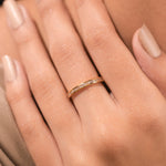 Woman's hand wearing a dainty yellow gold channel set baguette diamond wedding band. A minimal, elegant ring perfect for stacking or everyday wear.