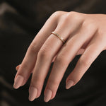 A dainty 14k yellow gold diamond stackable ring showcasing a continuous row of sparkling baguette gemstones worn lifestyle style on a ring finger.