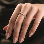 A yellow gold wedding band with vertically set baguette-cut diamonds with round prongs. This stackable fine jewelry piece is shown on a hand 