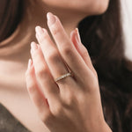 Yellow gold baguette cut diamond band on a model's finger, highlighting a luxury vertical prong-set diamond ring for women.