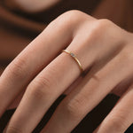 Hand wearing a dainty gold baguette diamond wedding band. This minimalist ring features a single horizontal stone, perfect for stacking.