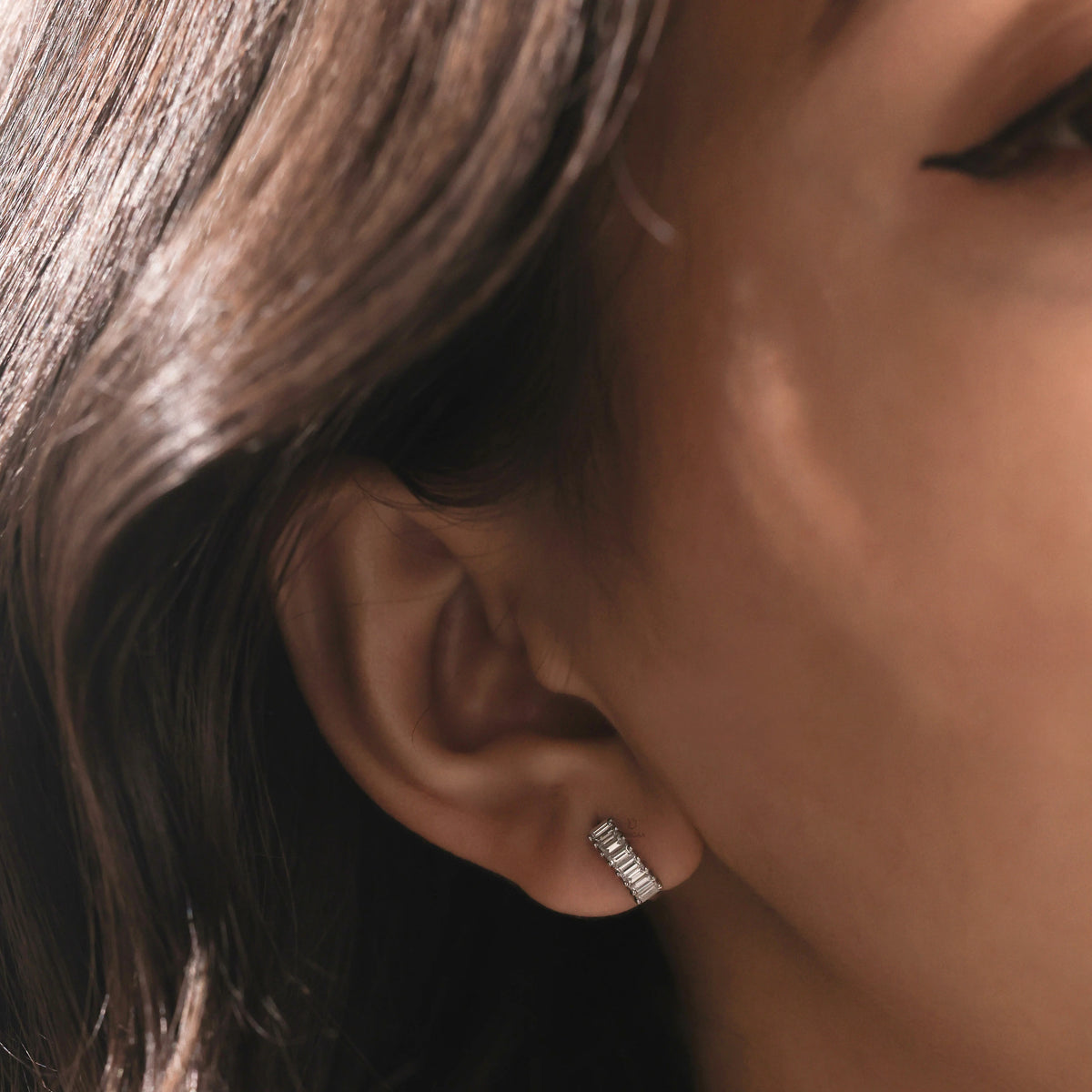 White gold baguette diamond hoop earrings styled in a lower lobe piercing to demonstrate real-life product fit, scale, and luxury shine.