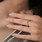 Model wearing a gold chevron ring with mixed baguette and round diamonds on her finger. Delicate V-shaped curved wedding band lifestyle shot.