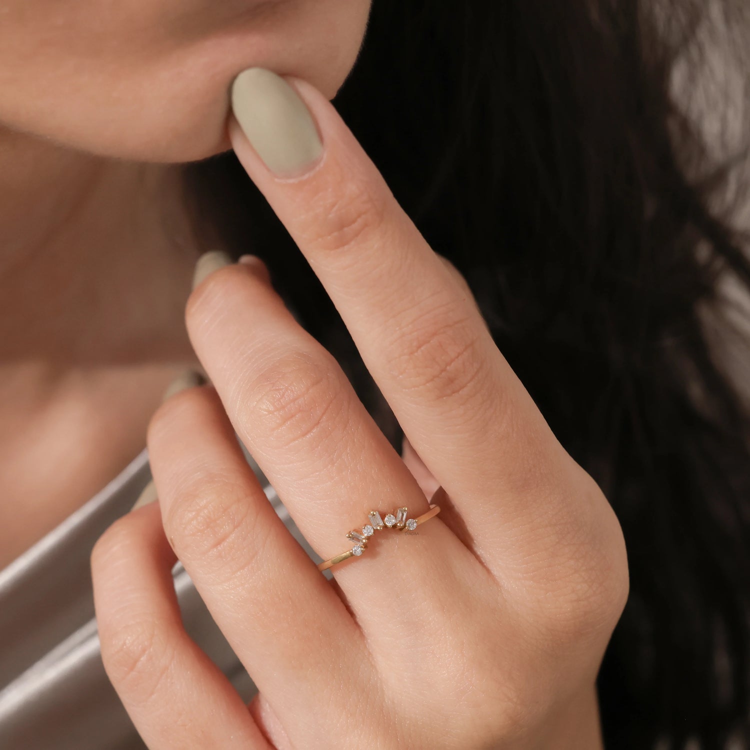 Model wearing a dainty gold tiara ring with baguette diamonds on her finger. Elegant curved crown wedding band lifestyle photo. 