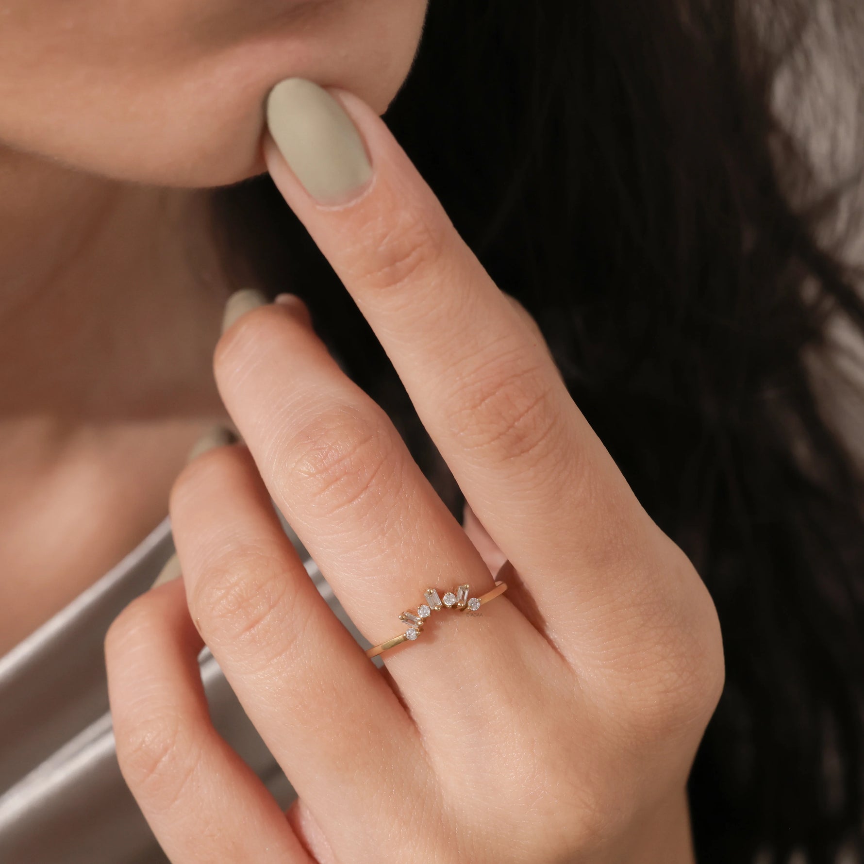 Model wearing a dainty gold tiara ring with baguette diamonds on her finger. Elegant curved crown wedding band lifestyle photo. 