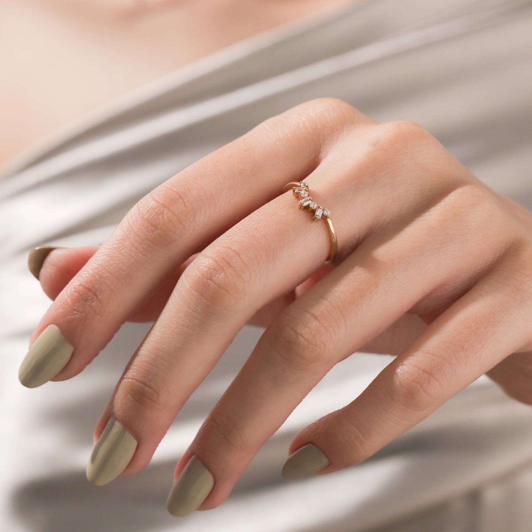 yellow  gold curved diamond ring with baguette and round stones worn on hand. Ideal minimalist stacking band or contoured wedding ring.