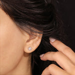 Close-up shot of a model wearing a 14K yellow gold prong-set baguette and round diamond stud earring styled on an earlobe piercing.