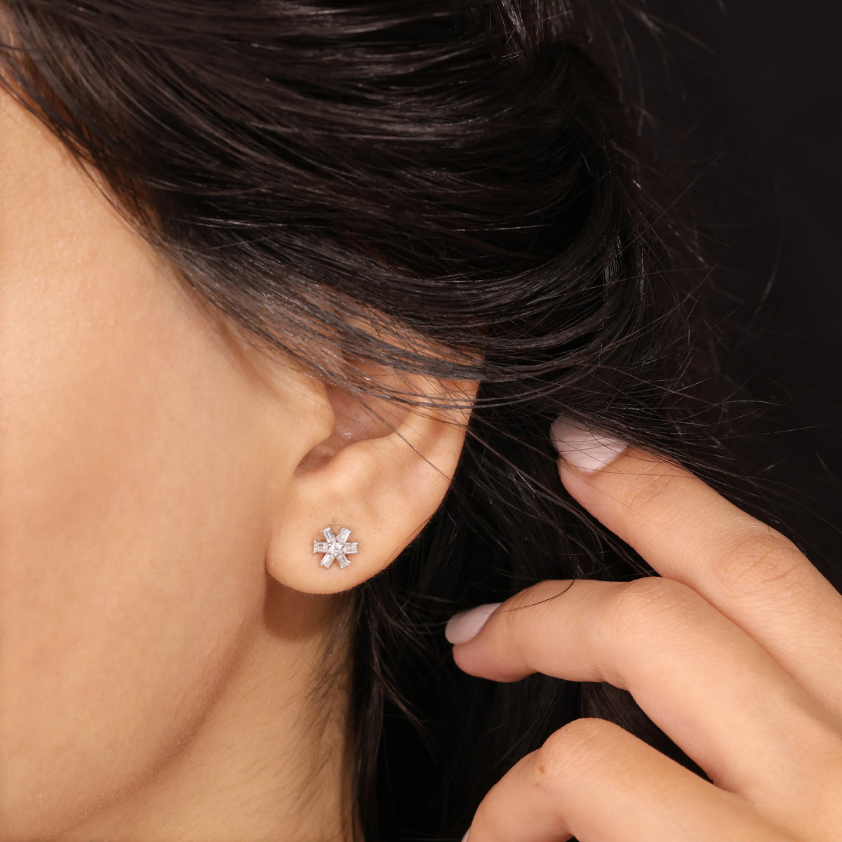 Close-up shot of a model wearing a 14K yellow gold prong-set baguette and round diamond stud earring styled on an earlobe piercing.