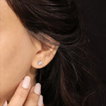 Close-up shot of a model wearing a 10K white gold prong-set baguette and round diamond stud earring styled on an earlobe piercing.