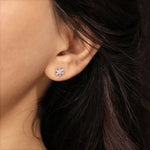 Close-up shot of a model wearing a 18K yellow gold prong-set baguette and round diamond stud earring styled on an earlobe piercing.