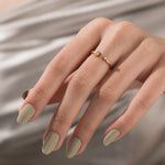 Dainty yellow gold open band ring with a tiny round and baguette cut diamond on a finger, perfect for fine jewelry inspiration.