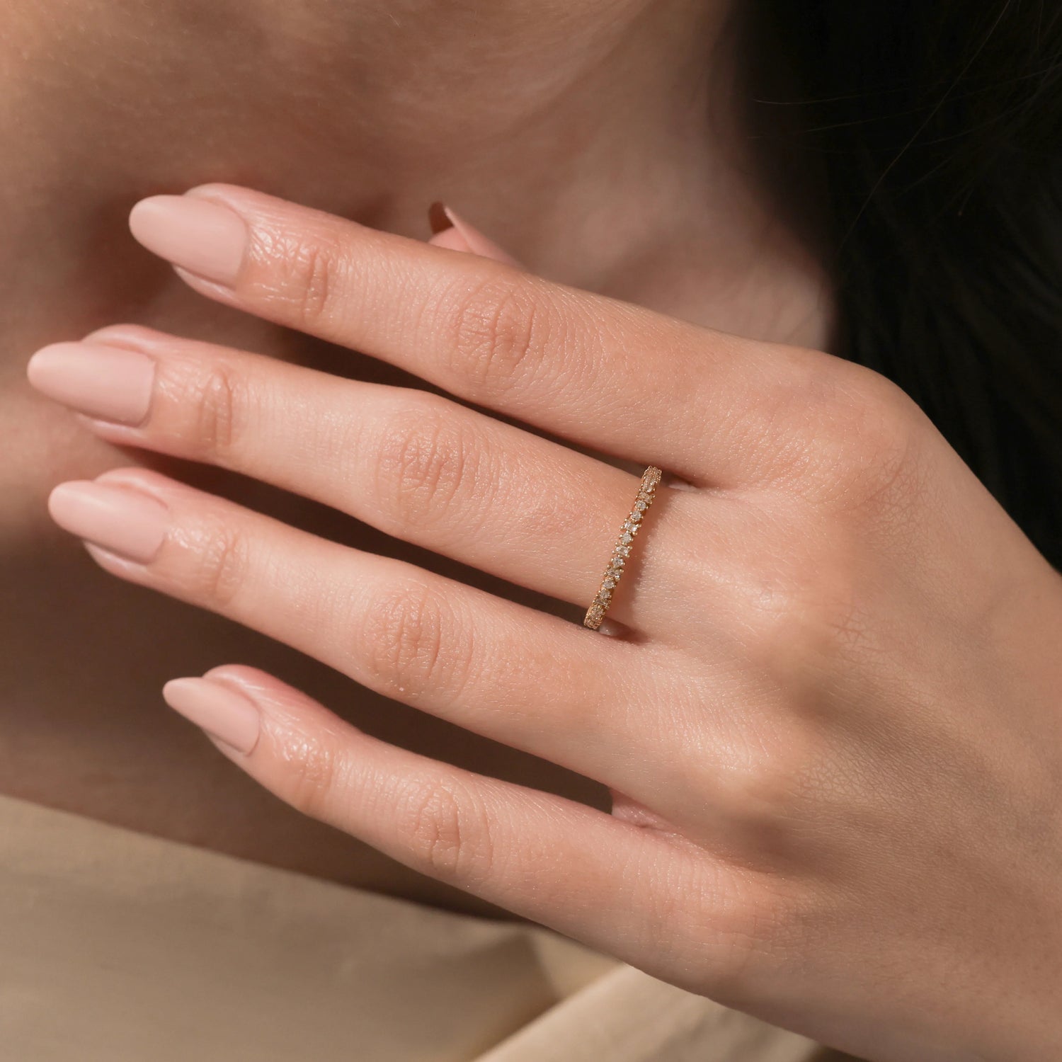 Woman wearing a delicate yellow gold band featuring alternating round and baguette diamonds on her finger.