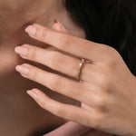 Unique yellow gold round and baguette diamond ring featuring an angled, zig-zag setting of alternating baguette and round diamonds worn on a woman's ring finger