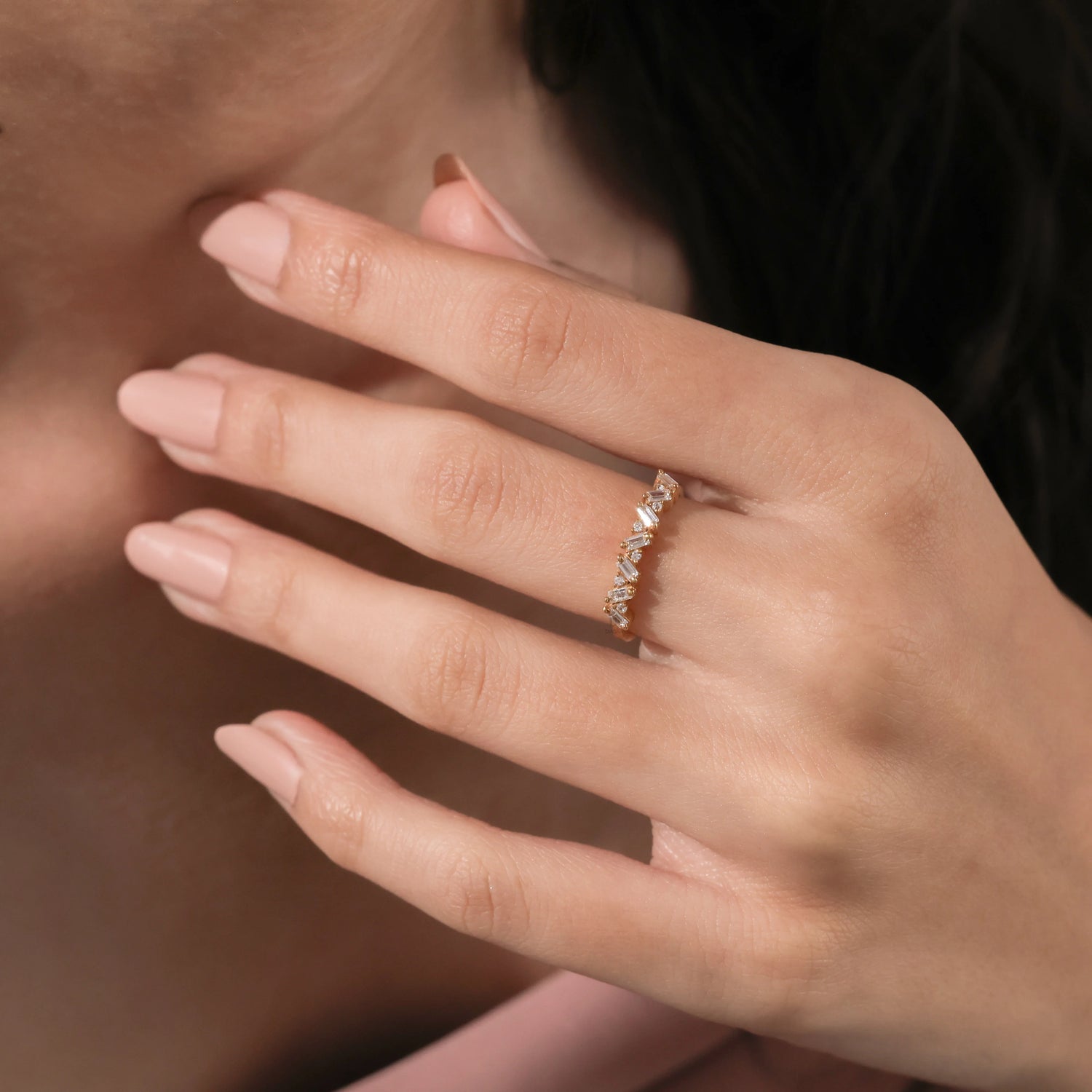 Unique yellow gold round and baguette diamond ring featuring an angled, zig-zag setting of alternating baguette and round diamonds worn on a woman's ring finger