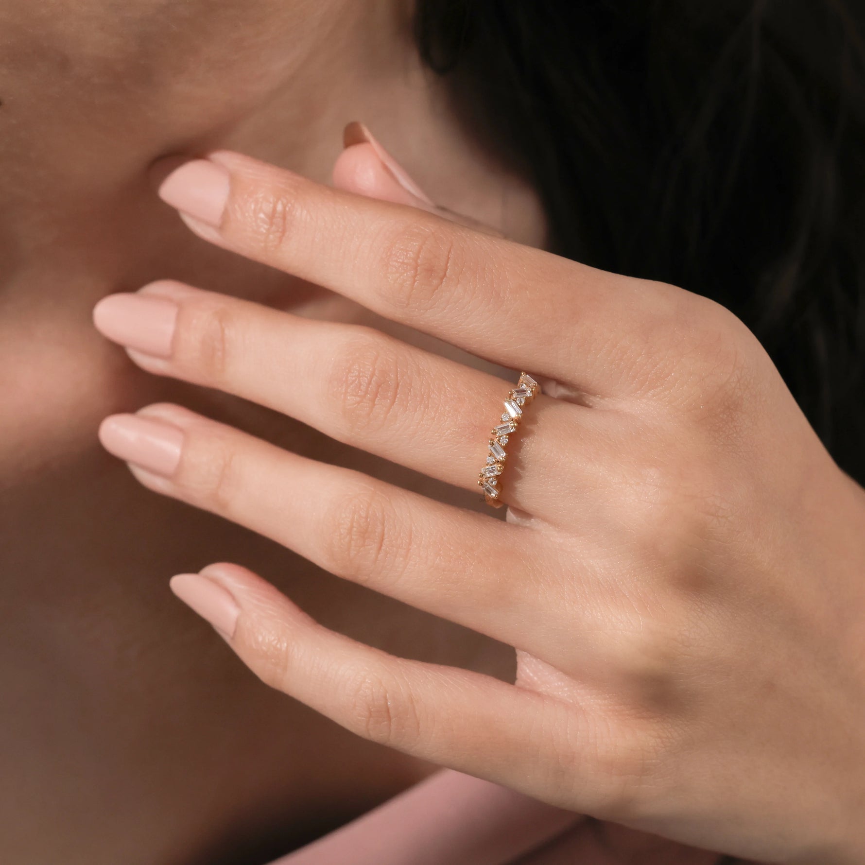 Unique yellow gold round and baguette diamond ring featuring an angled, zig-zag setting of alternating baguette and round diamonds worn on a woman's ring finger
