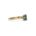 This yellow gold ring displayed in side view is made with a emerald solitaire diamond set in four-prong setting