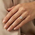 Yellow gold halo engagement ring featuring a round brilliant cut diamond on a woman's finger, showcasing elegant bridal jewelry.
