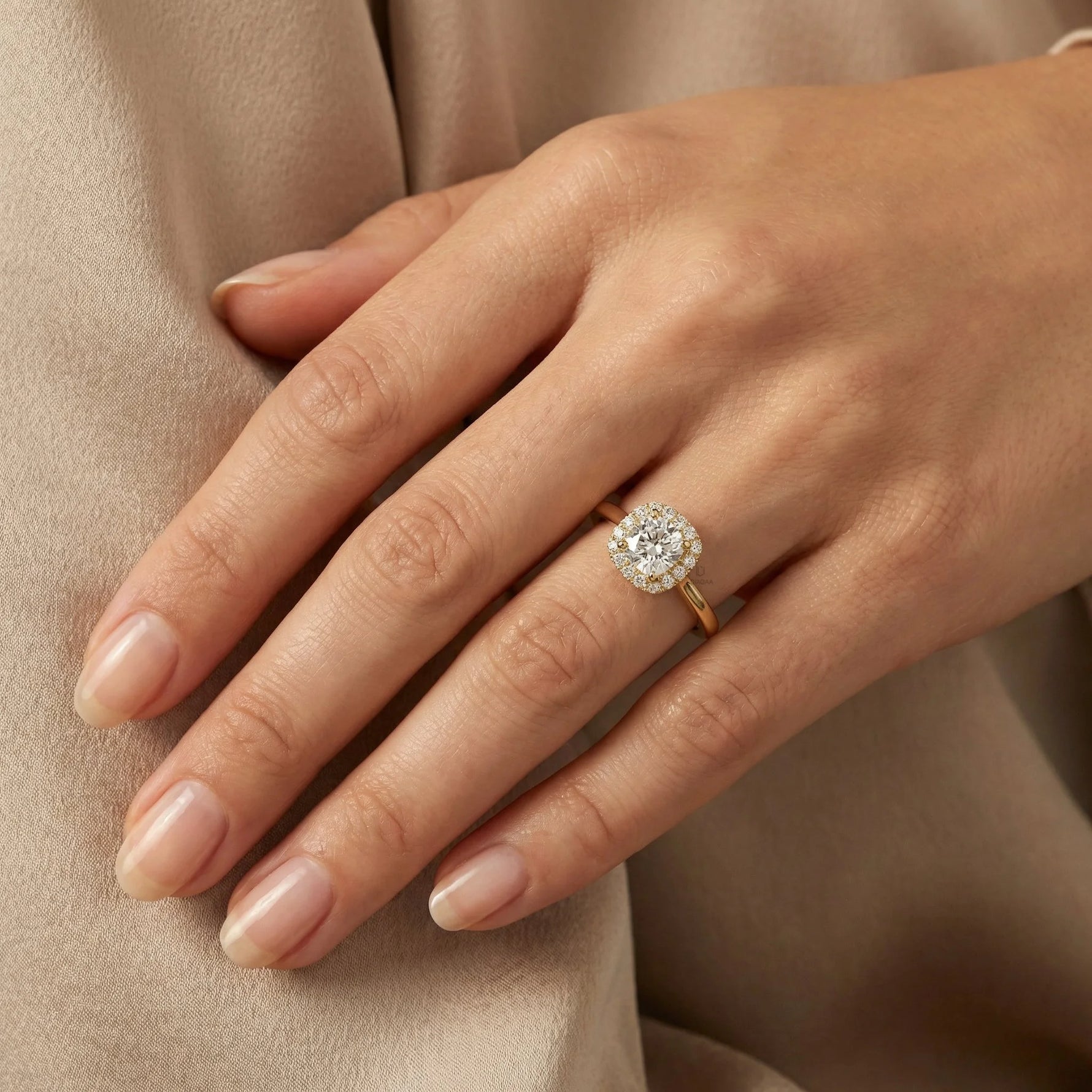 Yellow gold halo engagement ring featuring a round brilliant cut diamond on a woman's finger, showcasing elegant bridal jewelry.