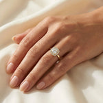 Cushion cut diamond halo engagement ring with a yellow gold band, worn on a hand.