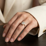 Cushion-cut diamond solitaire halo engagement ring set in 14k yellow gold with a round cut pavé and halo set band, beautifully modeled on a woman's hand.
