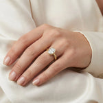 Oval cut diamond engagement ring with a yellow gold bezel setting worn on a woman's hand.