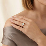 Modern yellow gold bezel solitaire ring with a cushion-shaped diamond and micro-pavé band, displayed gracefully on a woman’s ring finger for an elegant bridal look.