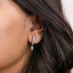  Women wearing round and emerald diamond dangling hoop earring styled on earlobe, shown in 18K white gold with a classic prong setting