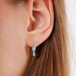 This white gold Dangling Emerald Diamond Hoop Earrings handmade with round brilliant-cut diamonds in pave setting and an emerald solitaire hanging at the bottom