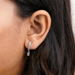  Women wearing round and emerald diamond dangling hoop earring styled on earlobe, shown in white gold with a classic prong setting