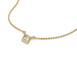 Angled view of a bezel-set princess Diamond necklace featuring a square solitaire diamond in a yellow gold frame with a white background.