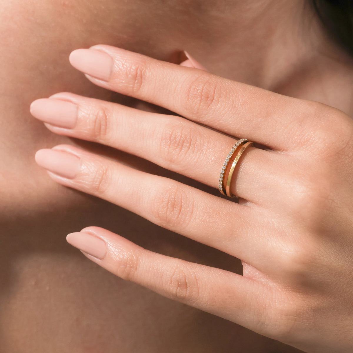 Yellow gold double band wedding ring featuring round diamond pavé accents, worn on a hand with nude nails to demonstrate everyday scale and style.