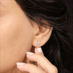Model wearing an elegant cluster-style emerald and round diamond stud earring with a prong setting in white gold.