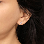 Model wearing an elegant cluster-style emerald and round diamond stud earring with a prong setting in yellow gold.