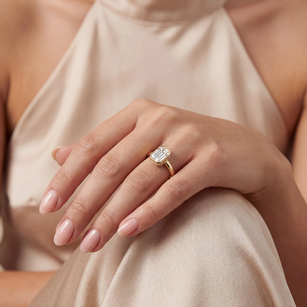 Woman wearing a yellow gold emerald-cut diamond Solitare engagement ring with a modern bezel setting ring.