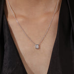Model wearing a classic 18K white gold Emerald Diamond necklace featuring a step-cut bezel-set solitaire pendant.