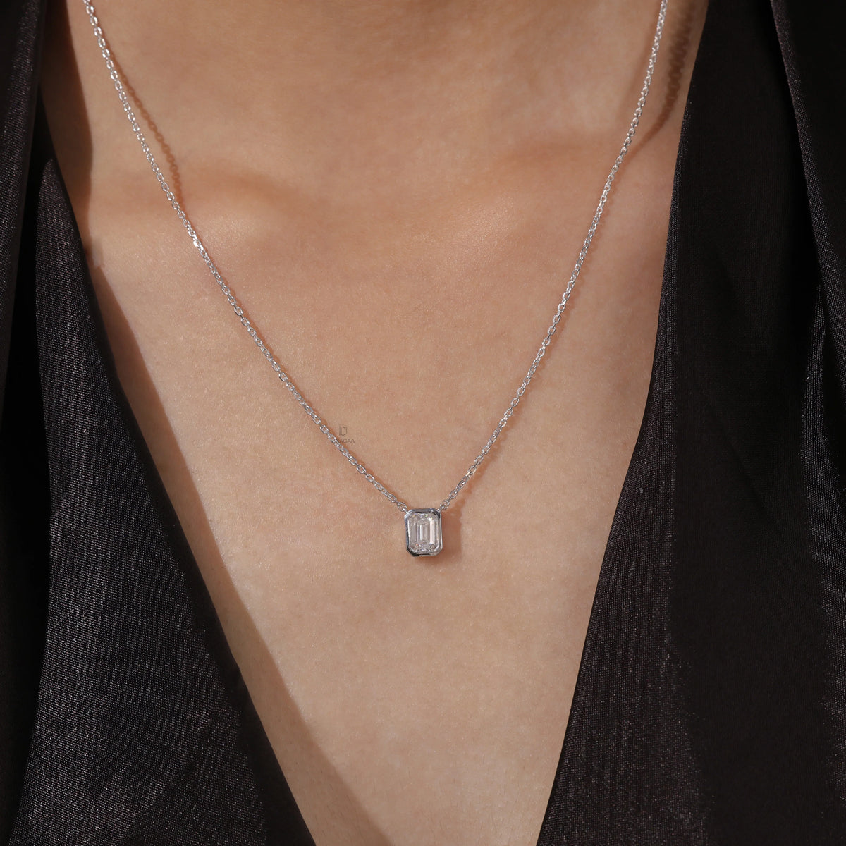 Model wearing a classic 18K white gold Emerald Diamond necklace featuring a step-cut bezel-set solitaire pendant.