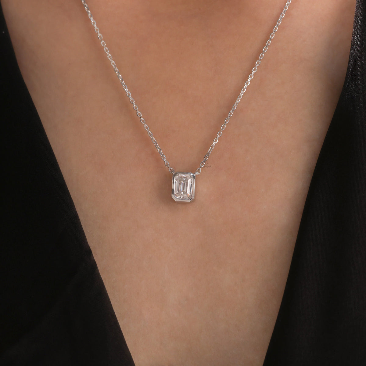 Model wearing a classic yellow gold Emerald Diamond necklace featuring a step-cut bezel-set solitaire pendant.