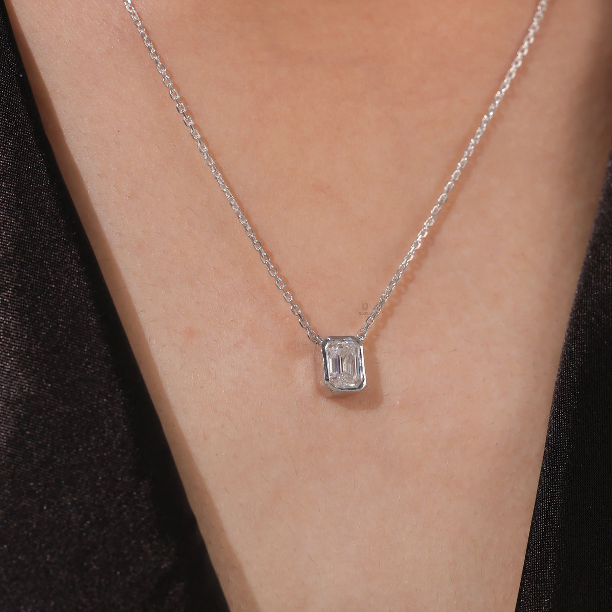 Model wearing a classic yellow gold Emerald Diamond necklace featuring a step-cut bezel-set solitaire pendant.