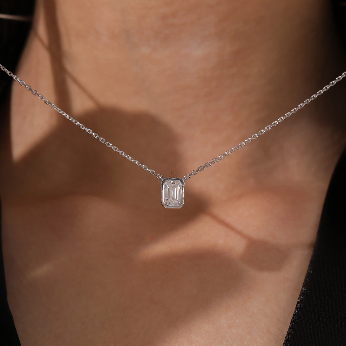 Model wearing a classic yellow gold Emerald Diamond necklace featuring a step-cut bezel-set solitaire pendant.