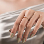 Yellow gold open cuff ring with an emerald cut diamond and round cut accent diamond on a woman's index finger.