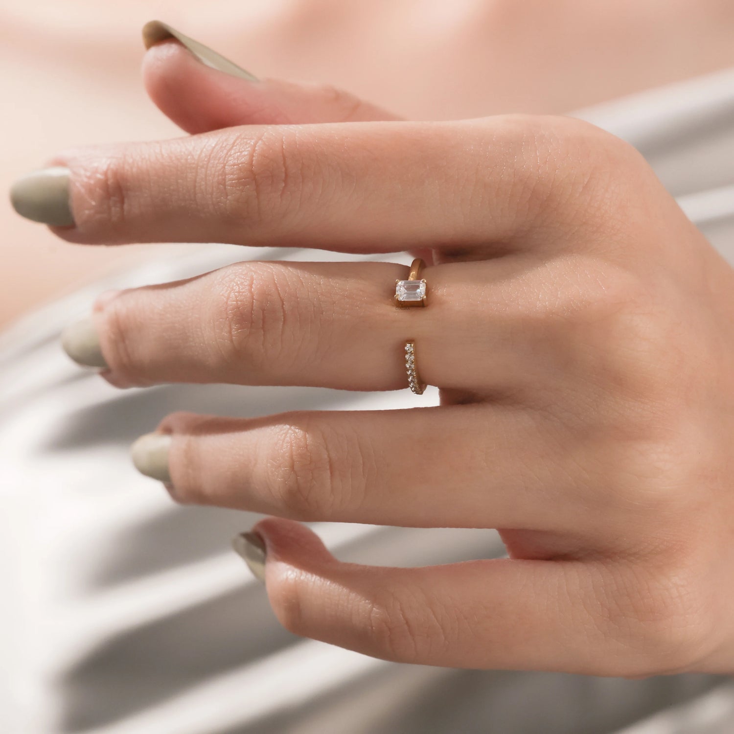 yellow Gold open cuff ring featuring a small emerald cut diamond and round cut pave set band worn on a woman's hand.